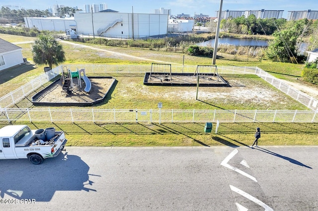 surrounding community with a playground, a water view, and a yard