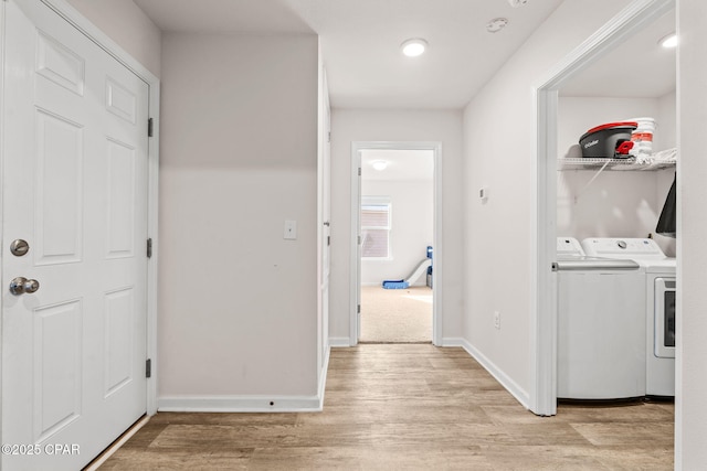 laundry room with light wood-type flooring, baseboards, laundry area, and washing machine and clothes dryer