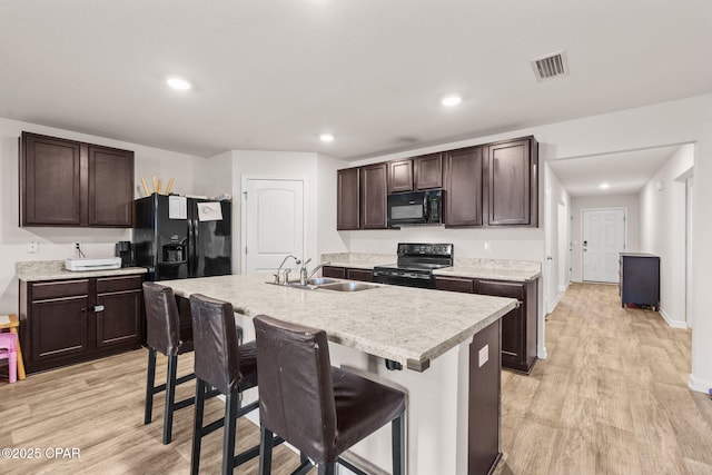 kitchen featuring a sink, visible vents, light wood-type flooring, and black appliances