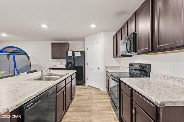 kitchen with dark brown cabinetry, light countertops, light wood-style flooring, black appliances, and a sink