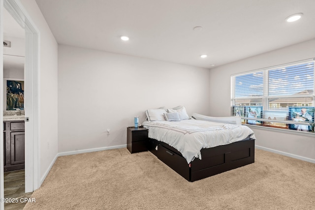 carpeted bedroom featuring recessed lighting, baseboards, and a sink