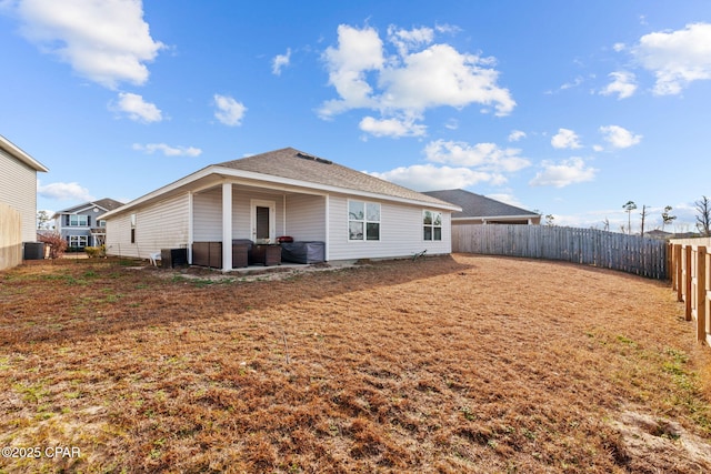 rear view of house with central air condition unit and a fenced backyard