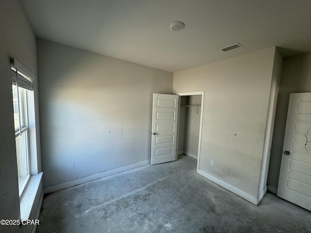 unfurnished bedroom with concrete flooring and a closet