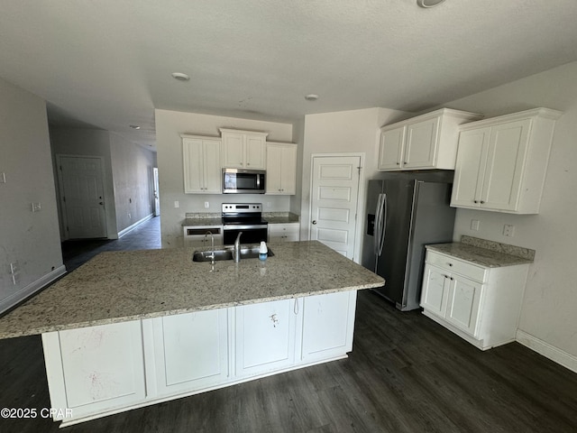 kitchen featuring sink, white cabinetry, light stone counters, appliances with stainless steel finishes, and a kitchen island with sink