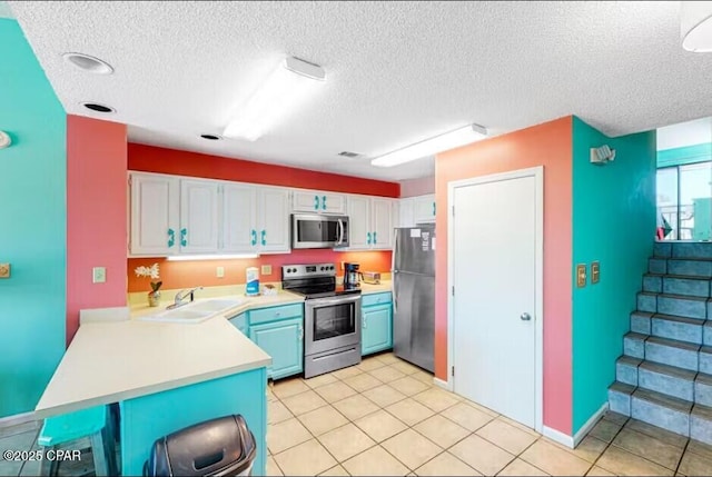 kitchen with sink, a textured ceiling, stainless steel appliances, and white cabinets