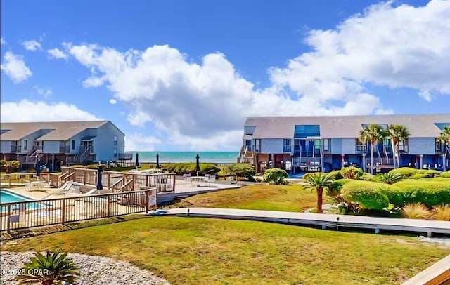 view of home's community with a water view, a swimming pool, a patio area, and a lawn