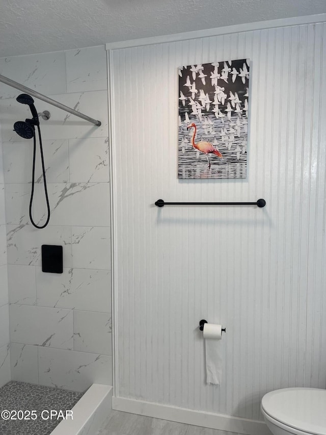 bathroom with tiled shower, a textured ceiling, and toilet