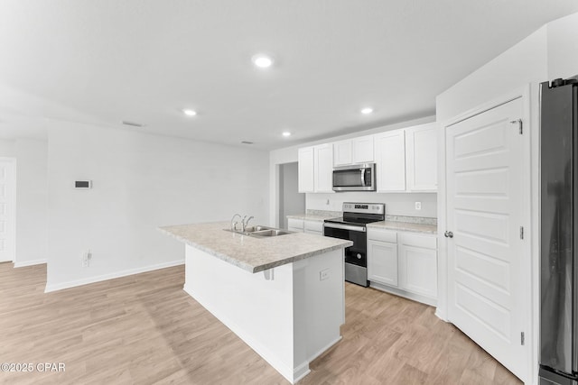 kitchen with sink, a kitchen island with sink, stainless steel appliances, light hardwood / wood-style floors, and white cabinets