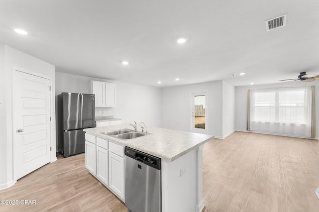 kitchen featuring appliances with stainless steel finishes, sink, white cabinets, a center island with sink, and light wood-type flooring