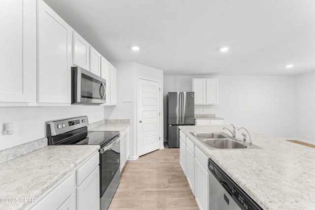 kitchen featuring appliances with stainless steel finishes, sink, white cabinets, and light hardwood / wood-style floors