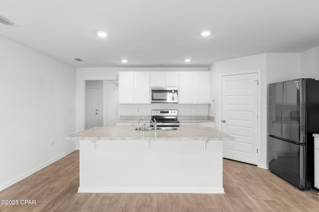 kitchen with appliances with stainless steel finishes, sink, an island with sink, and white cabinets