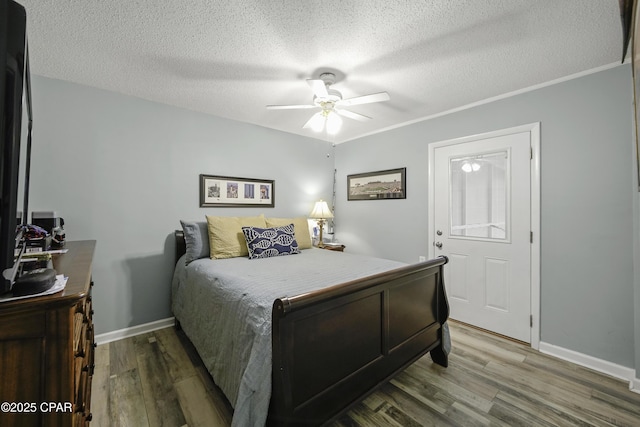 bedroom with ceiling fan, crown molding, dark hardwood / wood-style floors, and a textured ceiling