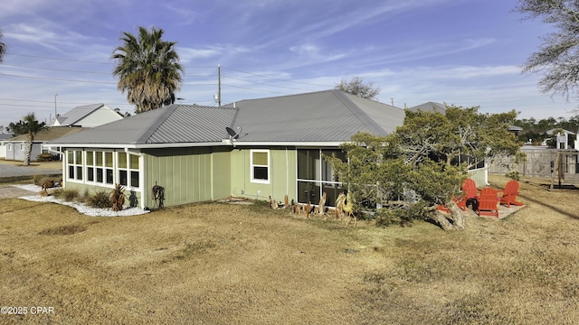 rear view of property with a lawn and a sunroom