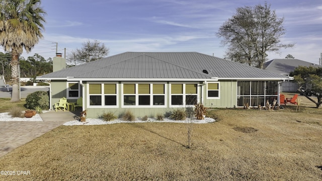 rear view of property featuring a yard and a sunroom