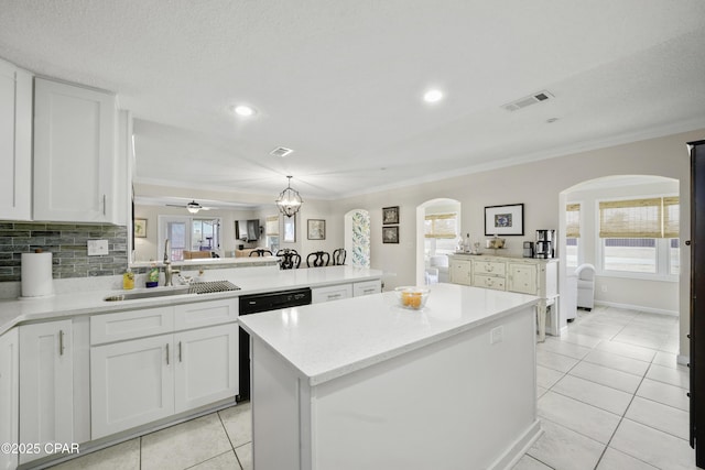 kitchen with a wealth of natural light, ornamental molding, white cabinets, and a kitchen island