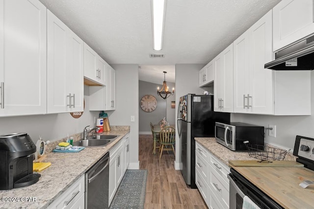 kitchen with sink, an inviting chandelier, stainless steel appliances, light hardwood / wood-style floors, and white cabinets