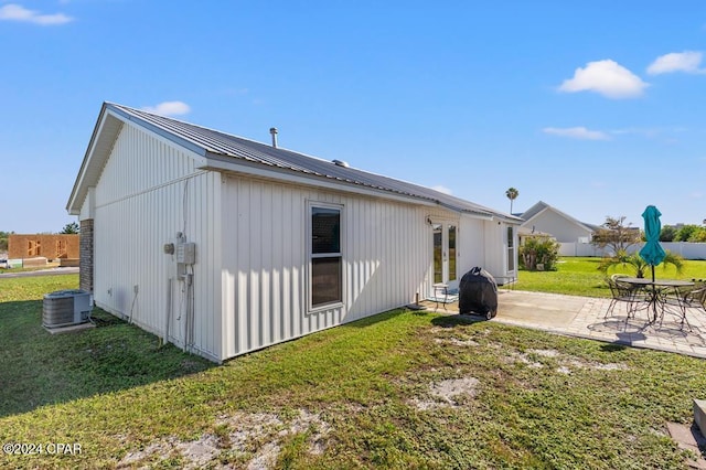 rear view of property with central AC unit, a lawn, and a patio