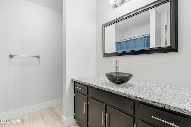 full bath featuring vanity, baseboards, and wood finished floors