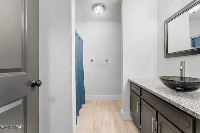 full bathroom with wood finished floors, vanity, and baseboards