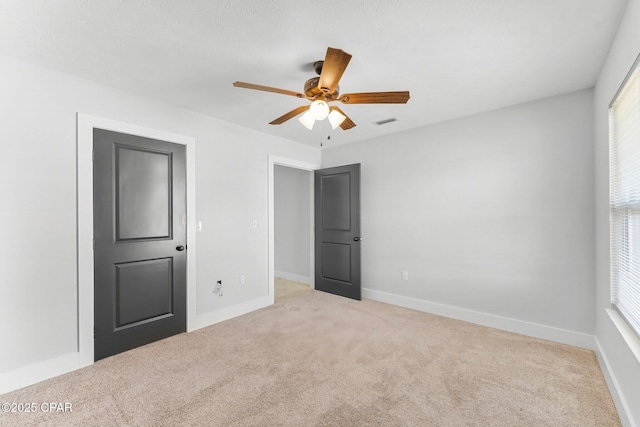 unfurnished bedroom with a ceiling fan, carpet, visible vents, and baseboards