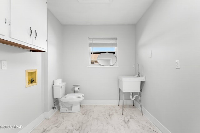 bathroom with marble finish floor, toilet, and baseboards