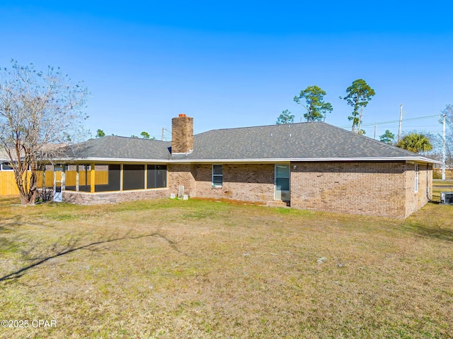 back of house with a shingled roof, brick siding, a lawn, and a chimney