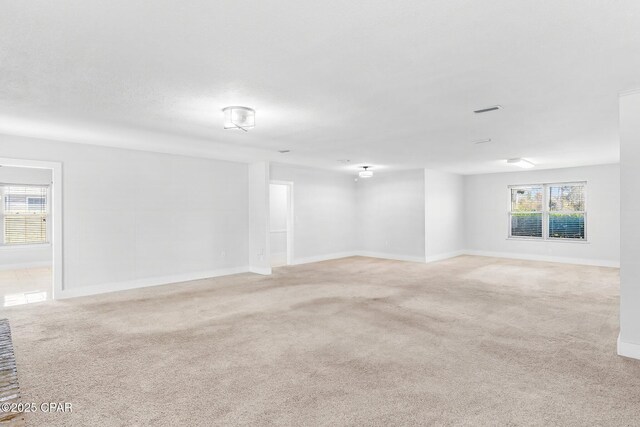 unfurnished room with light carpet, visible vents, and baseboards