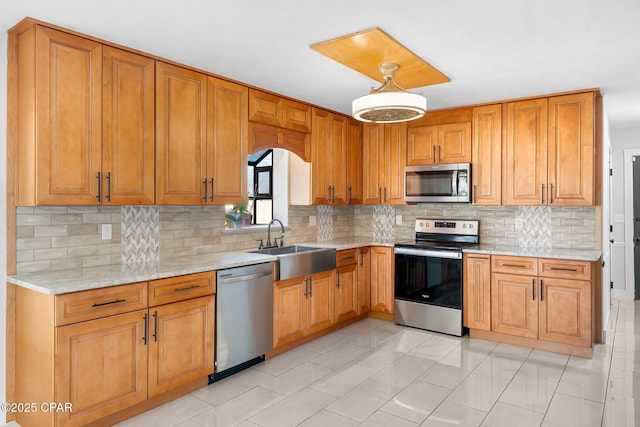 kitchen featuring decorative light fixtures, sink, backsplash, stainless steel appliances, and light stone countertops