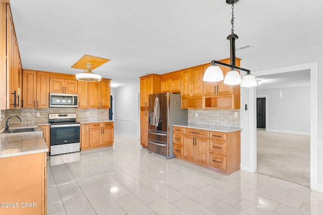 kitchen featuring hanging light fixtures, backsplash, sink, and appliances with stainless steel finishes