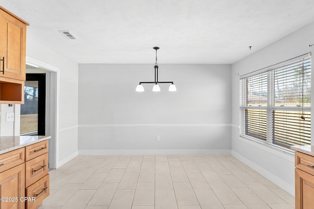 unfurnished dining area with a notable chandelier and a textured ceiling