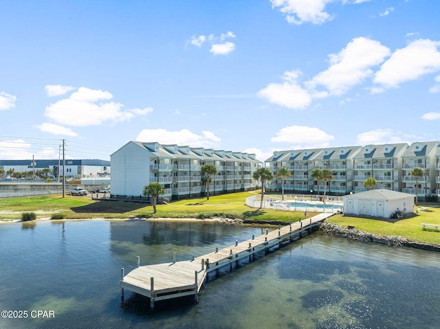 view of dock with a yard and a water view