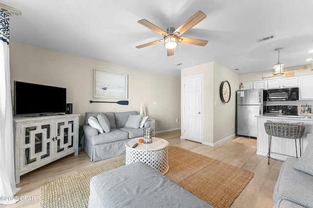 living room featuring ceiling fan and light hardwood / wood-style flooring