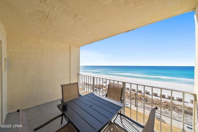 balcony with a water view and a view of the beach