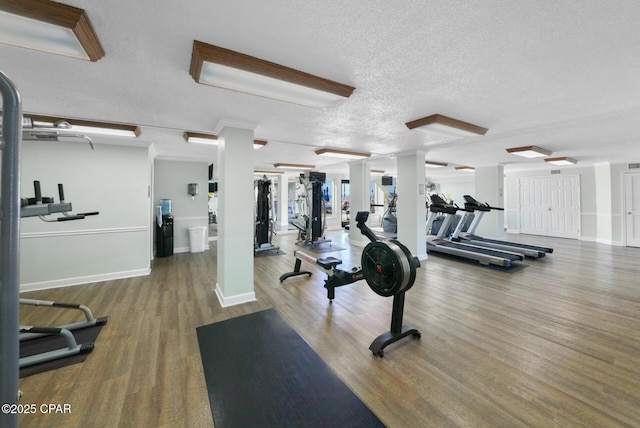 gym with a textured ceiling, baseboards, and wood finished floors