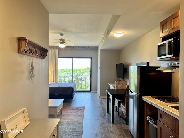 kitchen featuring ceiling fan, stainless steel appliances, dark hardwood / wood-style floors, and tile countertops