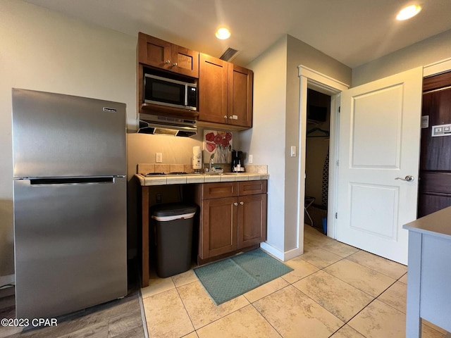 kitchen featuring light tile patterned floors, appliances with stainless steel finishes, a sink, and recessed lighting