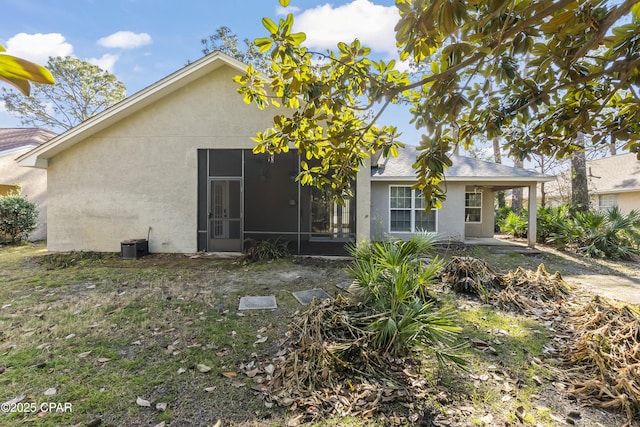 back of house with stucco siding and a sunroom