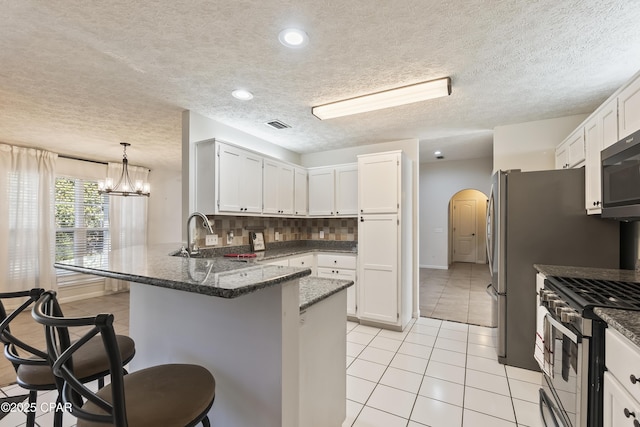 kitchen with arched walkways, a sink, a peninsula, stainless steel appliances, and a breakfast bar area