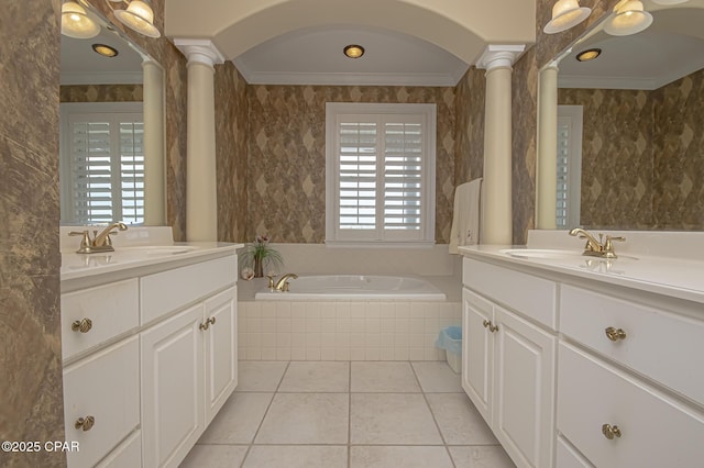 bathroom featuring tile patterned floors, ornate columns, crown molding, vanity, and tiled bath