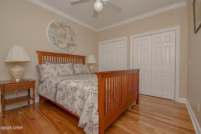 bedroom featuring ceiling fan, light hardwood / wood-style flooring, ornamental molding, and multiple closets