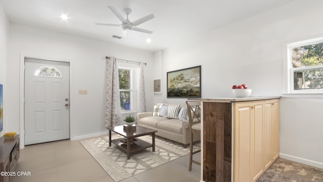 living room featuring baseboards, visible vents, and ceiling fan