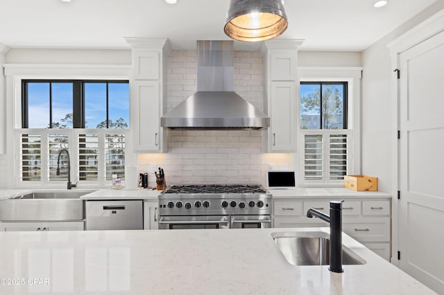 kitchen featuring white cabinetry, appliances with stainless steel finishes, sink, and wall chimney range hood