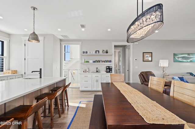 dining space with sink, an inviting chandelier, and light hardwood / wood-style flooring