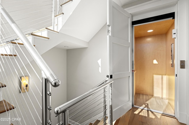 stairs featuring hardwood / wood-style flooring and elevator