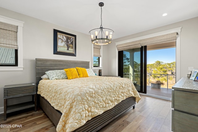 bedroom featuring wood-type flooring, a chandelier, and access to outside