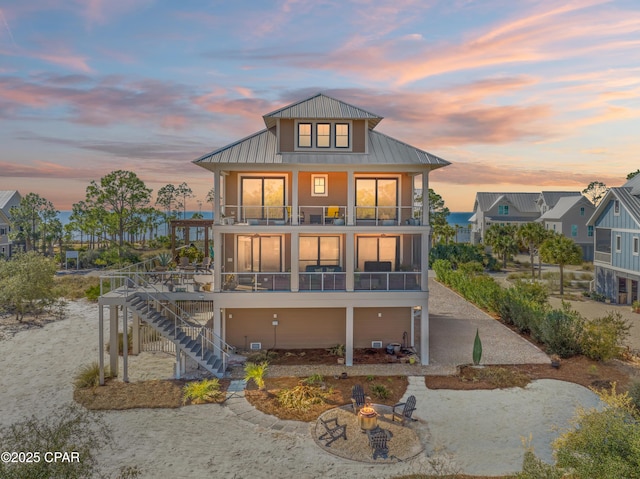 back house at dusk with a fire pit and a balcony