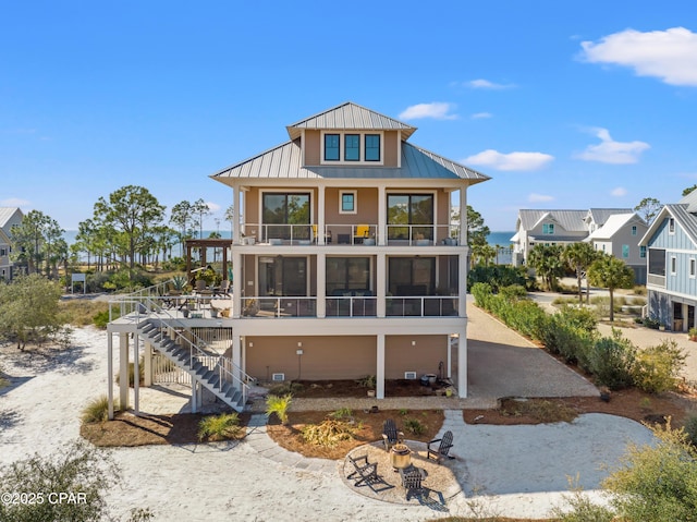 rear view of house featuring a balcony, an outdoor fire pit, and a sunroom