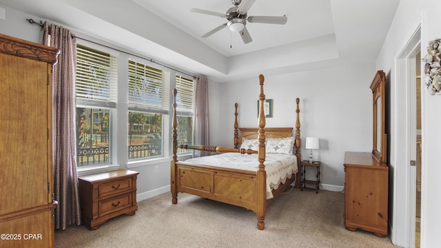 carpeted bedroom featuring ceiling fan and a tray ceiling