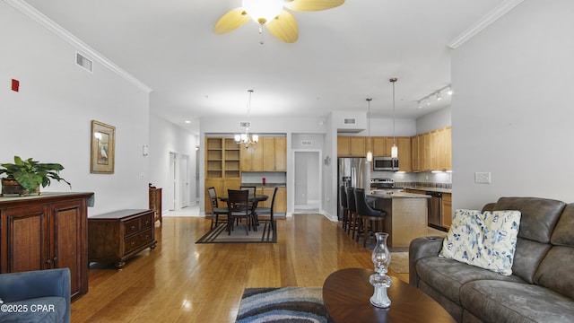 living room featuring crown molding, hardwood / wood-style flooring, and ceiling fan with notable chandelier