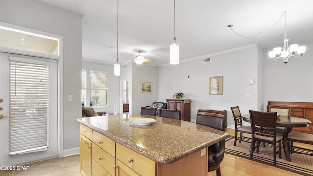 kitchen featuring hanging light fixtures, crown molding, ceiling fan with notable chandelier, and a center island